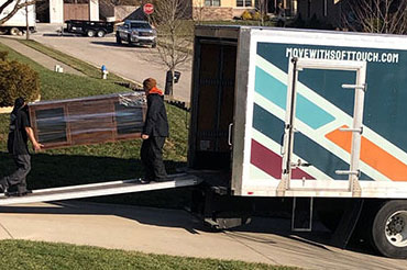 Two Soft Touch Moving professionals loading a Soft Touch Moving truck